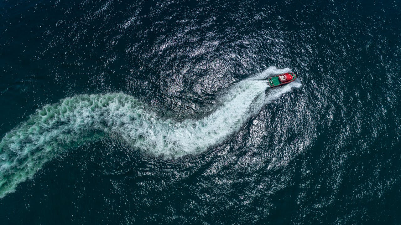 Drone shot capturing a motorboat making dynamic waves in the ocean, viewed from above.